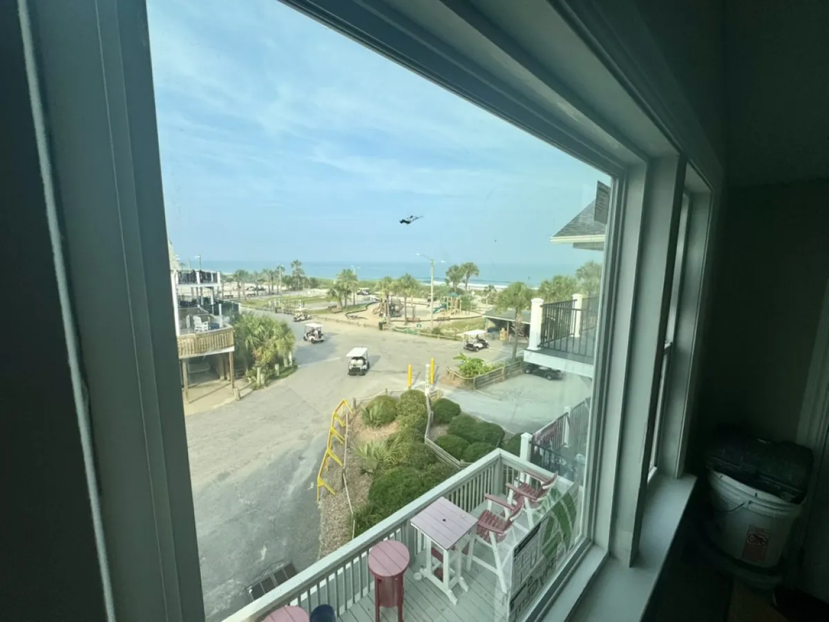This image presents a wide sea view with palm trees, golf carts, and outdoor seating on a porch area. The relaxed setting implies easy access to the ocean, opportunities for people-watching, and the enjoyment of outdoor dining or leisure activities—all while embracing the coastal lifestyle.