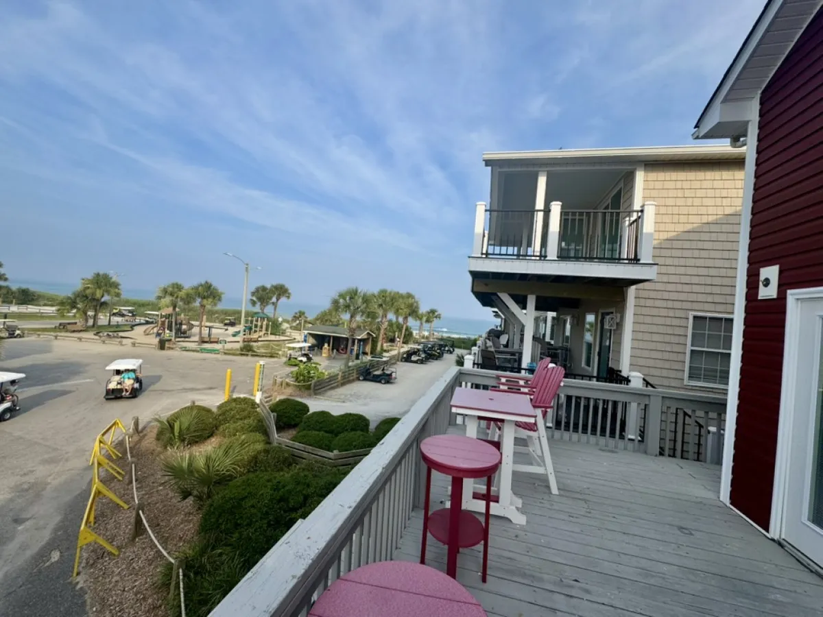 This image presents a stunning beach view with nearby houses and a vehicle on the road, evoking a sense of proximity to the ocean and easy access to outdoor relaxation. The view hints at the private balcony and ocean vistas described in the section and the seamless blend of indoor comfort with beachside enjoyment.